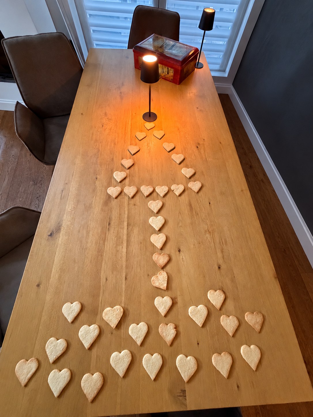 Herzplätzchen als Weihnachtsbaum auf Gregors Holztisch mit warm leuchtenden Tischlampen