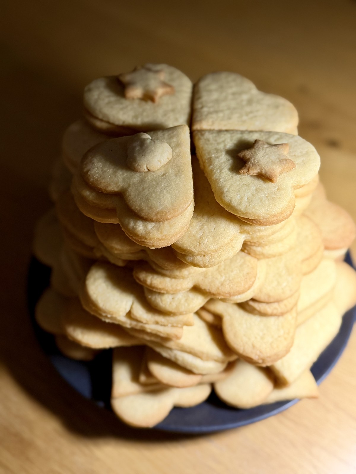 Selbst gebackene Plätzchen mit verschiedenen ausgestochenen Formen auf einem Teller gestapelt