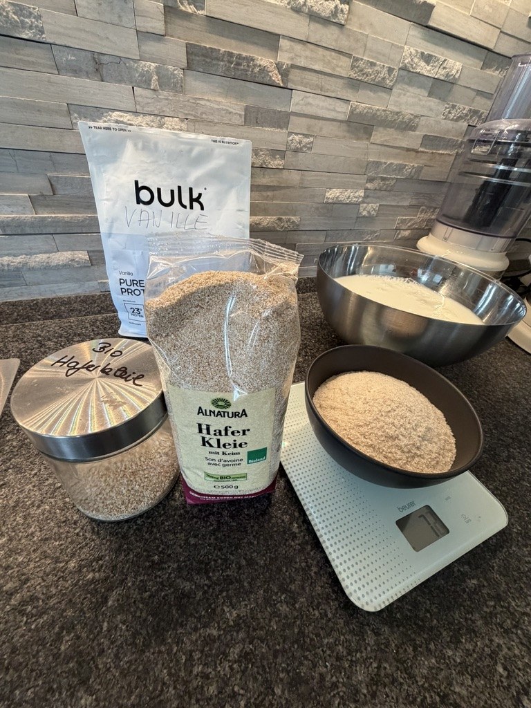 Vanille-Whey, Haferkleie, abgewogene Flohsamenschalen und Rührschüssel in Gregors Küche