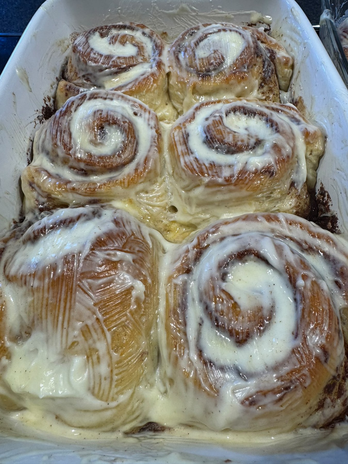Sechs fertige Zimtschnecken mit cremigem Frischkäse-Frosting in der weißen Form